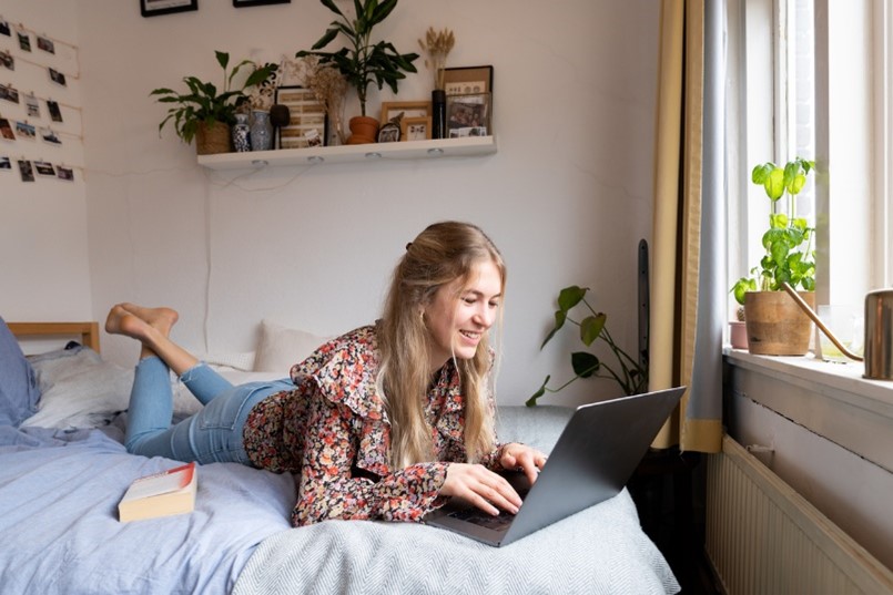 Female student on laptop in bed